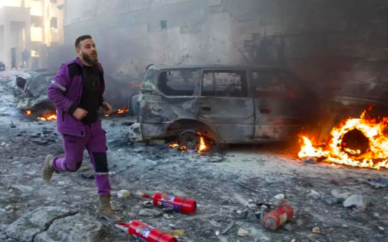 A first responder rushes through the aftermath of shelling that targeted hospitals and displaced camps in Idlib, northwest Syria.